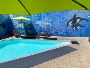 una piscina con sombrilla y un mural de delfines en Ambassador Motor Inn, en Tauranga