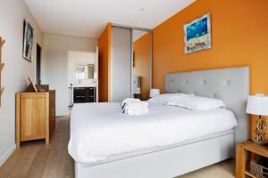 Un dormitorio con una cama blanca con una pared naranja. en Appartement des Asphodèles - Welkeys, en La Teste-de-Buch