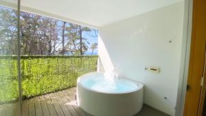 uma banheira na casa de banho com uma janela em 葉山 - Nowhere but Hayama em Hayama