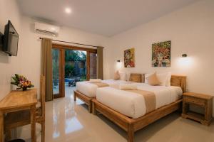 a bedroom with two beds and a television at Mag Canggu Bali By Hospitality Bali in Canggu