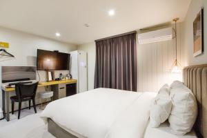 um quarto de hotel com uma cama branca e uma secretária em Brown-Dot Hotel Minam em Busan