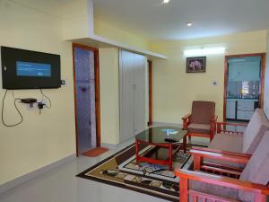 een woonkamer met een tv en een tafel en stoelen bij MISBA HOMESTAY in Kodaikānāl