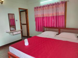 1 dormitorio con 1 cama con manta roja y espejo en MISBA HOMESTAY en Kodaikānāl
