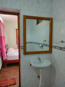 baño con lavabo, espejo y cama en MISBA HOMESTAY en Kodaikānāl