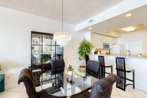 comedor y cocina con mesa de cristal y sillas en Navarre Beach Regency 308, en Navarre