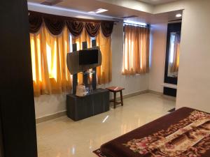 a bedroom with a bed and a flat screen tv at Hotel Satpura Safari in Pachmarhī