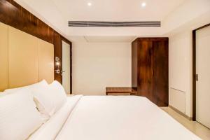 a bedroom with a white bed and a wooden door at Ramee Techome in Mumbai