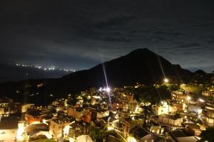 eine Stadt in der Nacht mit einem Berg im Hintergrund in der Unterkunft TopHome 9 in Jiufen