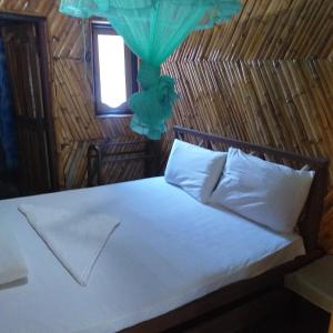 a bedroom with a white bed with a window at Scoop Cabana Kitesurfing in Kalpitiya