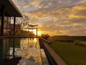 a swimming pool with a sunset in the background at MAUA Nusa Penida Bali in Nusa Penida