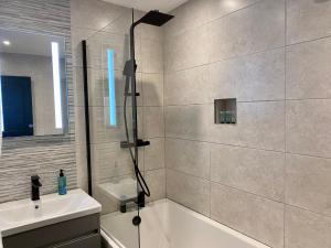 a bathroom with a shower and a tub and a sink at Eden Retreats Serviced Apartments in Morecambe