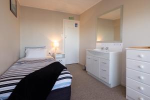 a small bedroom with a bed and a sink at Oamaru Backpackers in Oamaru