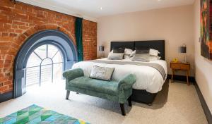 um quarto com uma cama, uma cadeira e uma parede de tijolos em The Old Chapel Apartments em Edwinstowe