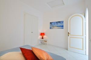 a white room with a door and a table with a lamp at Beth in Praiano