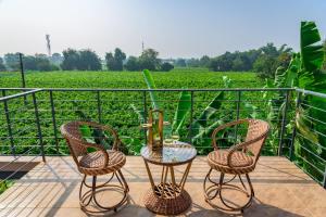 three chairs and a table on a balcony with a vineyard at SaffronStays Eden - 3BR vineyard-side pool villa with jacuzzi, farm dining, stargazing deck & lawns for celebrations in Nashik