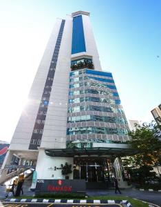 um edifício alto com pessoas a andar na frente dele em Ramada Suites by Wyndham Kuala Lumpur City Centre em Kuala Lumpur