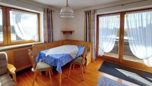 ein Esszimmer mit einem Tisch und 2 Fenstern in der Unterkunft Ferienwohnung Nr 3, Lechbruck-Gründl, Allgäu in Prem