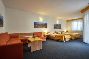 Habitación de hotel con 2 camas y sofá en Penzion Volařík en Dolní Dunajovice
