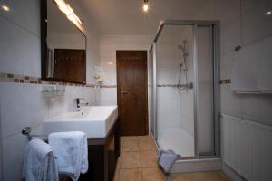 uma casa de banho com um lavatório, um chuveiro e uma banheira em Pension Göbel em Willingen