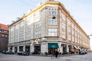 a woman riding a bike in front of a large building at Kings Garden 2 by Daniel&Jacob's in Copenhagen