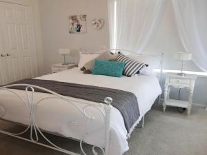 a bedroom with a white bed with two tables and a window at Sealark in Callala Bay