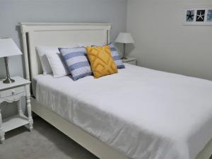 a white bed with blue and white pillows on it at Sealark in Callala Bay