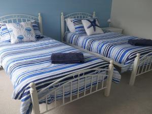 two beds with blue and white striped sheets in a room at Sealark in Callala Bay