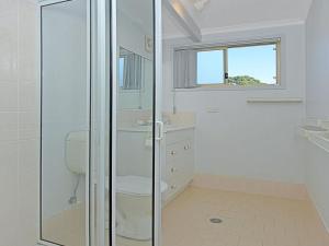 a bathroom with a toilet and a glass shower at Sealark in Callala Bay
