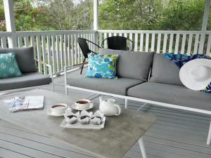 a coffee table with a couch and cups on a porch at Sealark in Callala Bay