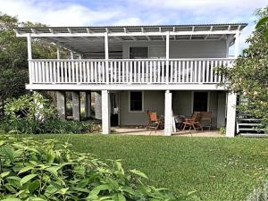 a white house with a deck and chairs on a yard at Sealark in Callala Bay