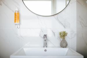 a bathroom sink with a mirror and a vase of flowers at Cosmo Napa Boutique Hotel in Ayia Napa