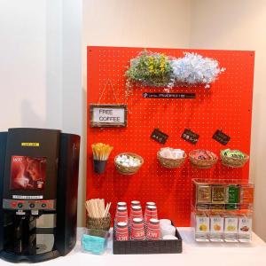 a red wall with a coffee maker and some plants at Hotel Promote Hakodate in Hakodate