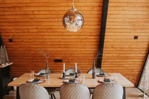 a wooden table with chairs and a wooden wall at Harmony Villa Lupeni Straja in Lupeni