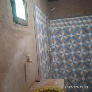 ein Bad mit einer Dusche mit blauen und weißen Fliesen in der Unterkunft Chegaga Berber Camps in M’hamid El Ghizlane