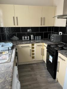 的住宿－Milnrow Road - Spacious 3 bed house，厨房配有白色橱柜和黑炉灶烤箱。