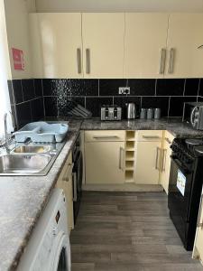 a kitchen with white cabinets and a sink and a dishwasher at Milnrow Road - Spacious 3 bed house 