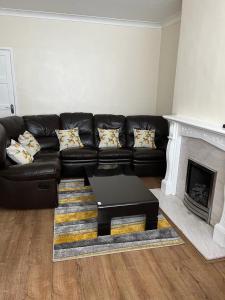 a black leather couch in a living room with a fireplace at Milnrow Road - Spacious 3 bed house 