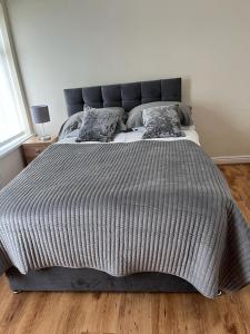 a large bed with a gray comforter in a bedroom at Milnrow Road - Spacious 3 bed house 