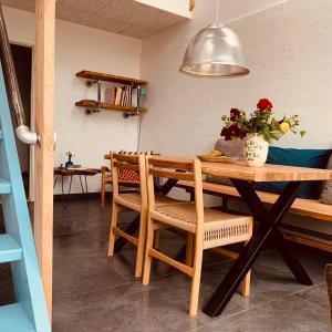 a dining room table and chairs with a vase of flowers at Rikke og Franks Svineri in Lemvig