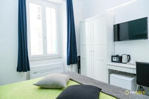 a bedroom with a bed with blue curtains and a television at Lia Rooms in La Spezia