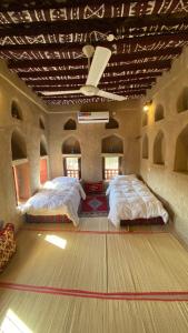 two beds in a room with a dance floor at Alqalah Inn in Al Ḩamrāʼ