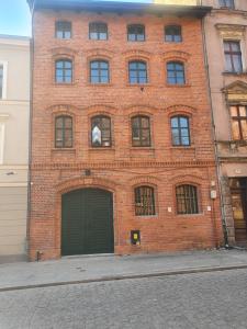 a red brick building with a green garage at Miodowa Faktoria # 4 in Toruń