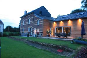 a large house with a patio and a lawn at B&B Au coin des sources in Sart-lez-Spa