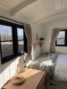 a small bedroom with a bed and windows at Peaceful Shepherd’s Hut in beautiful countryside. in Linlithgow