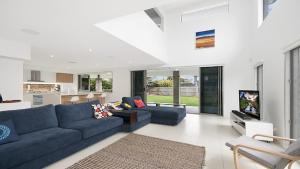 sala de estar con sofá azul y TV en The Palms - Lennox Head en Lennox Head