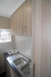 a kitchen with a sink and wooden cabinets at Carstens Garden Cottages in Kimberley