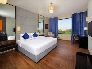 a bedroom with a large white bed with blue pillows at Essentia Luxury Hotel Indore in Indore