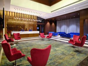 a waiting room with red chairs and blue tables at Essentia Luxury Hotel Indore in Indore