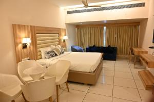 a hotel room with a large bed and chairs at Rang Lords Inn Bharuch in Bharuch