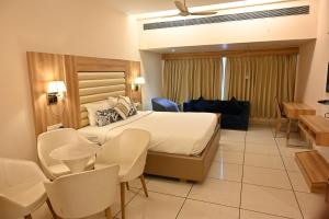 Rang Lords Inn Bharuch في Bharuch: غرفة فندقية بسرير وكراسي كبيرة